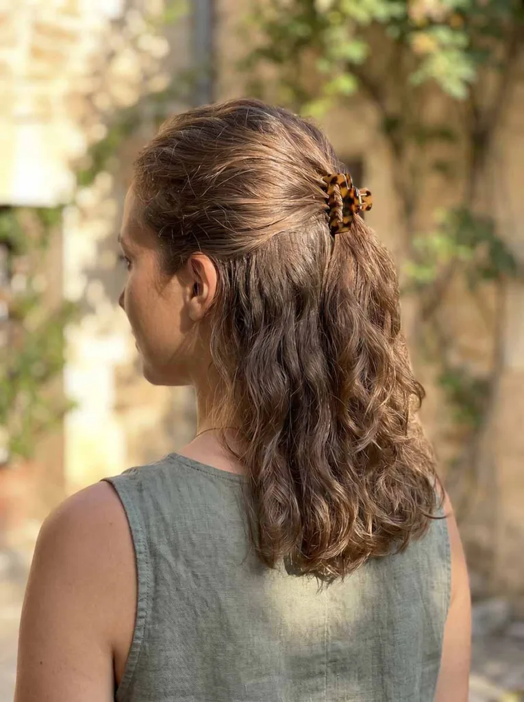 Woman with a half-up wavy bob, top section pinned at the crown, loose waves falling underneath
