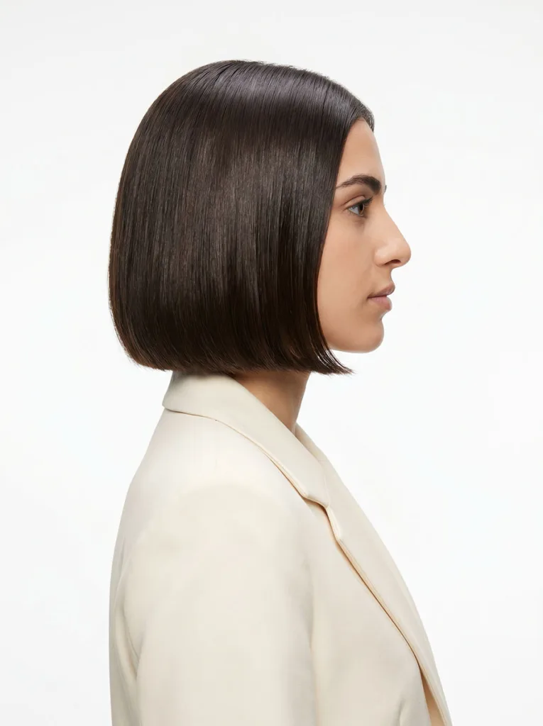 jaw-length glass bob right-facing profile on Middle Eastern woman, dark brown hair, ivory blazer, white studio background