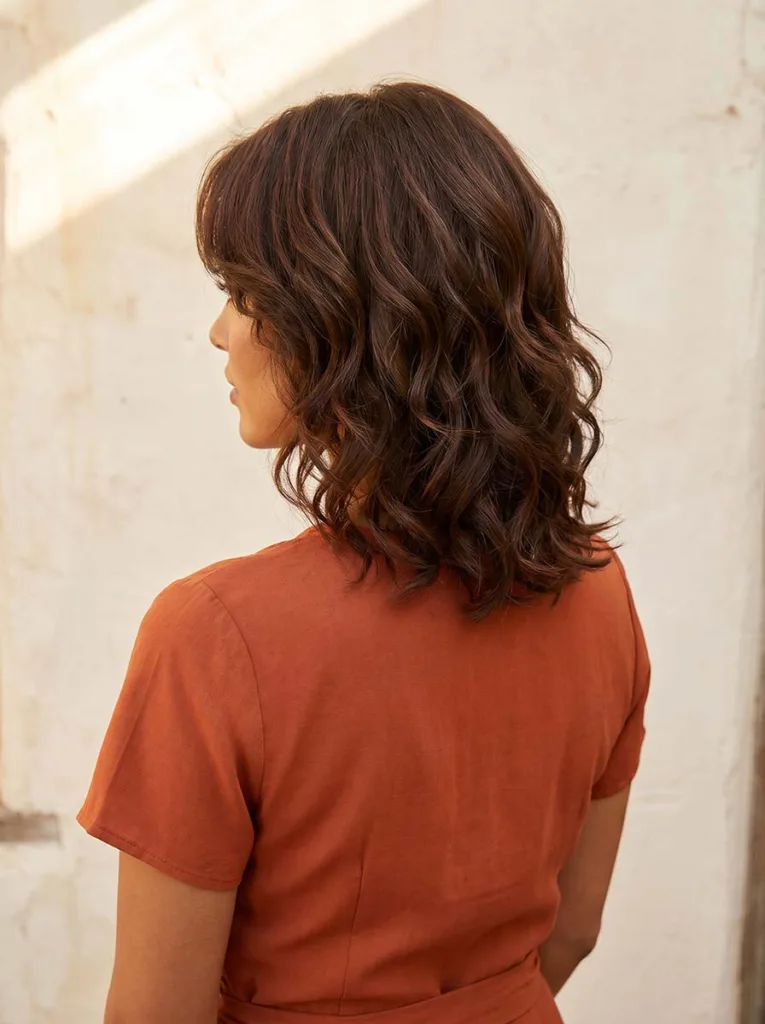 Woman with a layered shoulder-length wavy bob, visible layers adding volume and shape to the waves