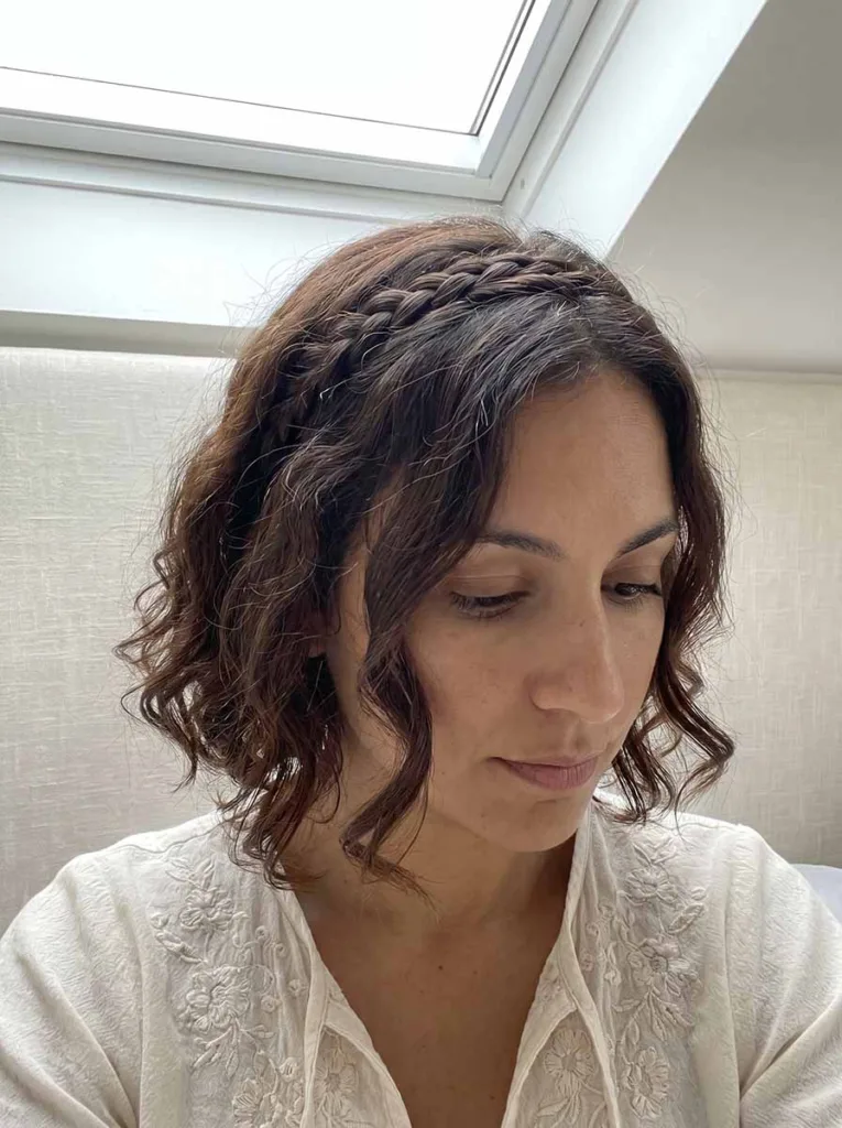 Woman with a wavy bob and a thin braided accent woven along the crown, bohemian hair detail