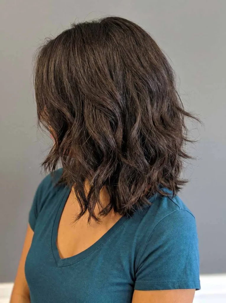 Woman with thick hair wearing a layered razored wavy bob, weight-removed texture with natural bounce