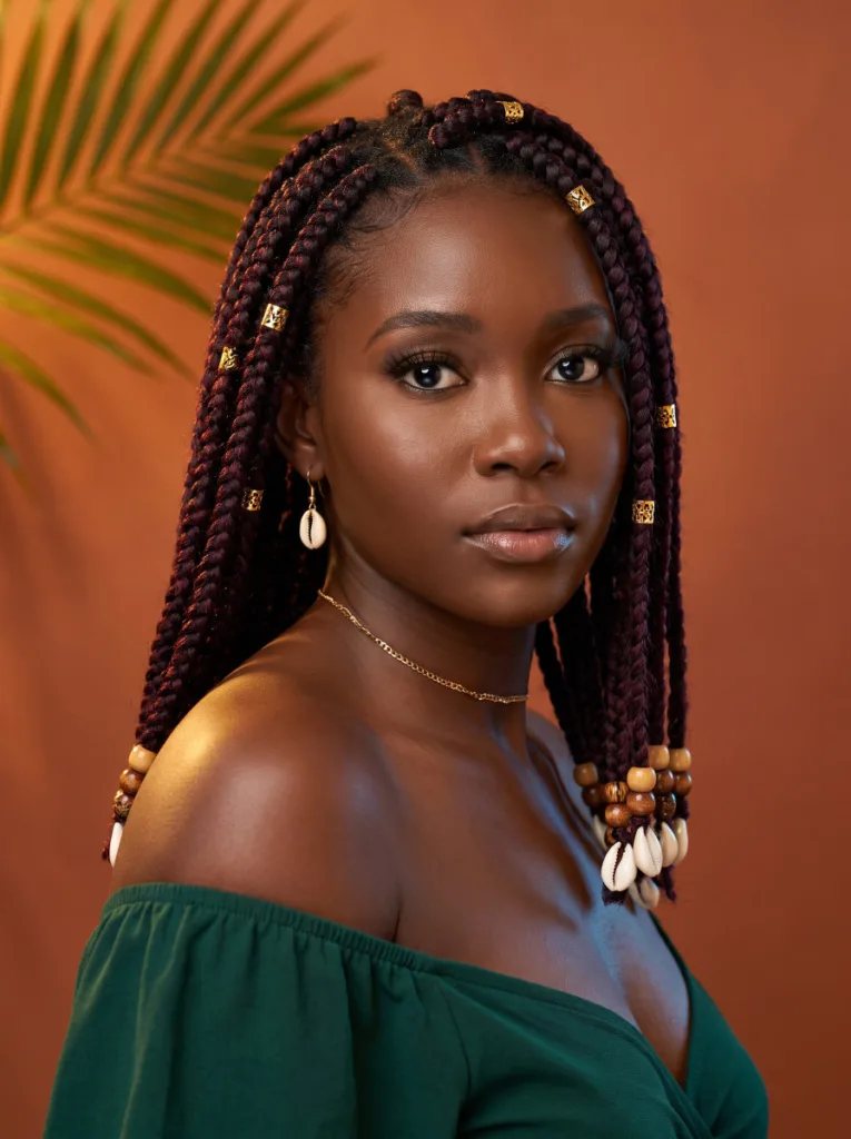 Beautiful young African woman with knotless braids adorned with gold cuffs and wooden beads