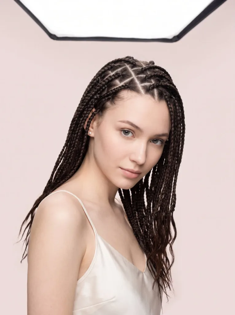 Young woman with dark espresso knotless braids showing geometric triangle parting across the scalp