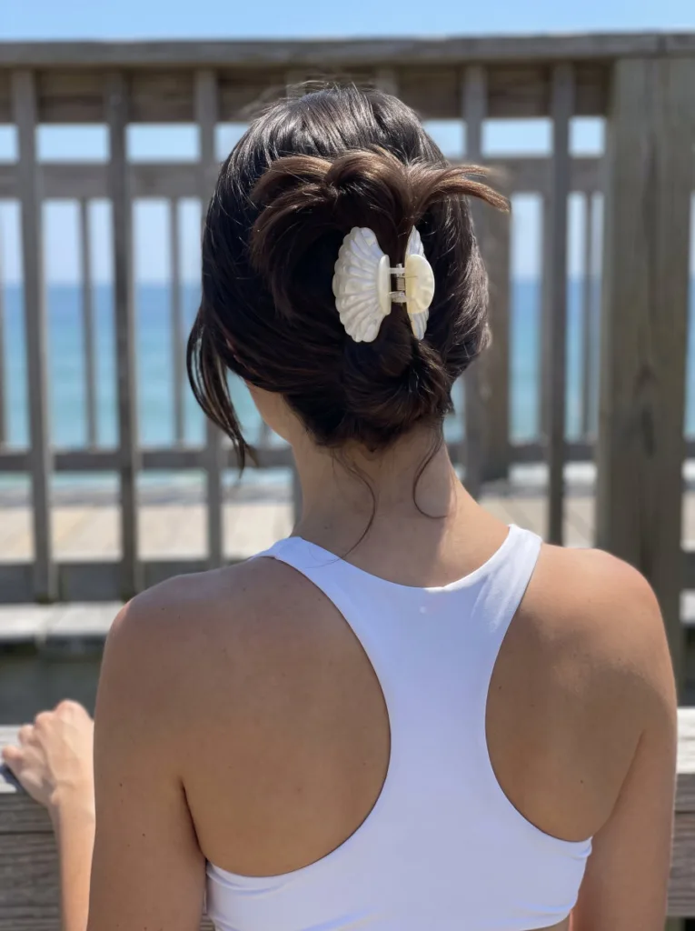 Classic low twisted shell clip bun at the nape on straight brunette hair at the beach