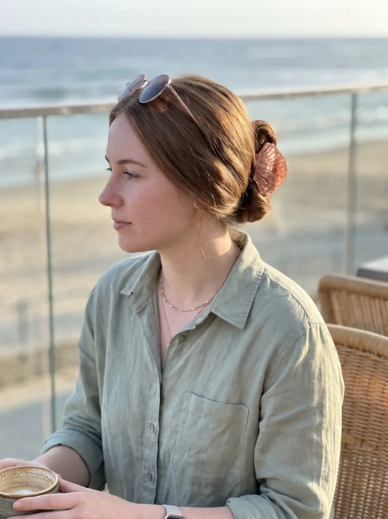Side-swept shell clip bun behind the ear on medium hair with ocean background