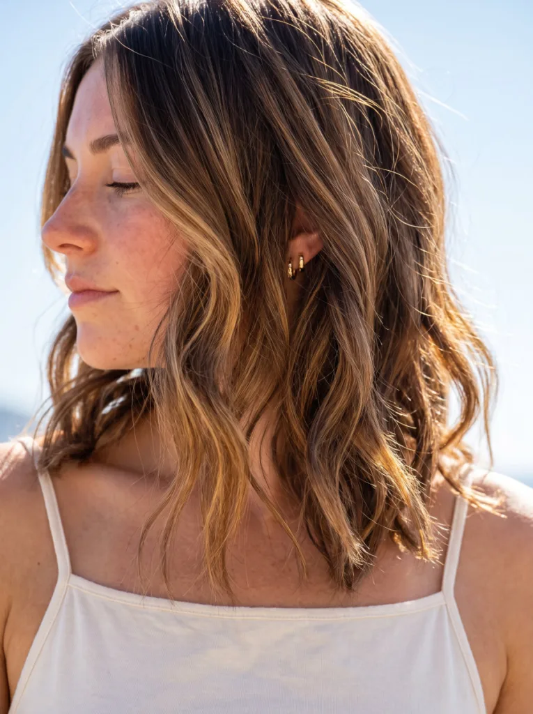 Close-up of sun-kissed balayage coastal cowgirl waves catching natural sunlight