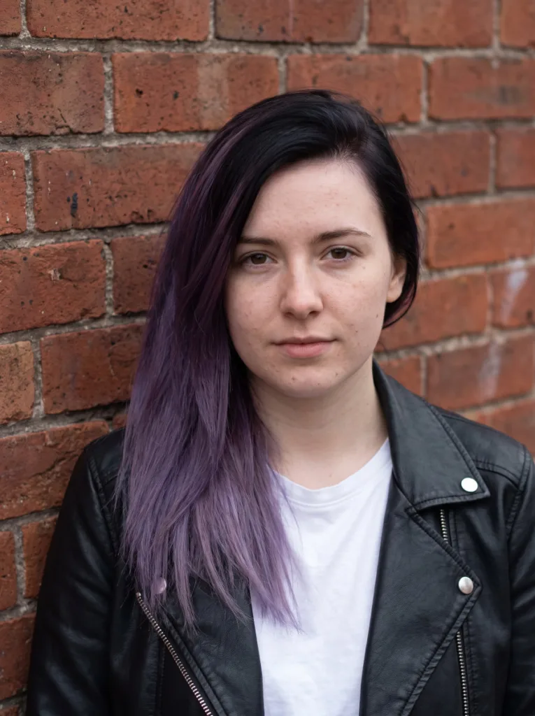 Woman with black to violet ombre hair color and visible root-to-tip transition