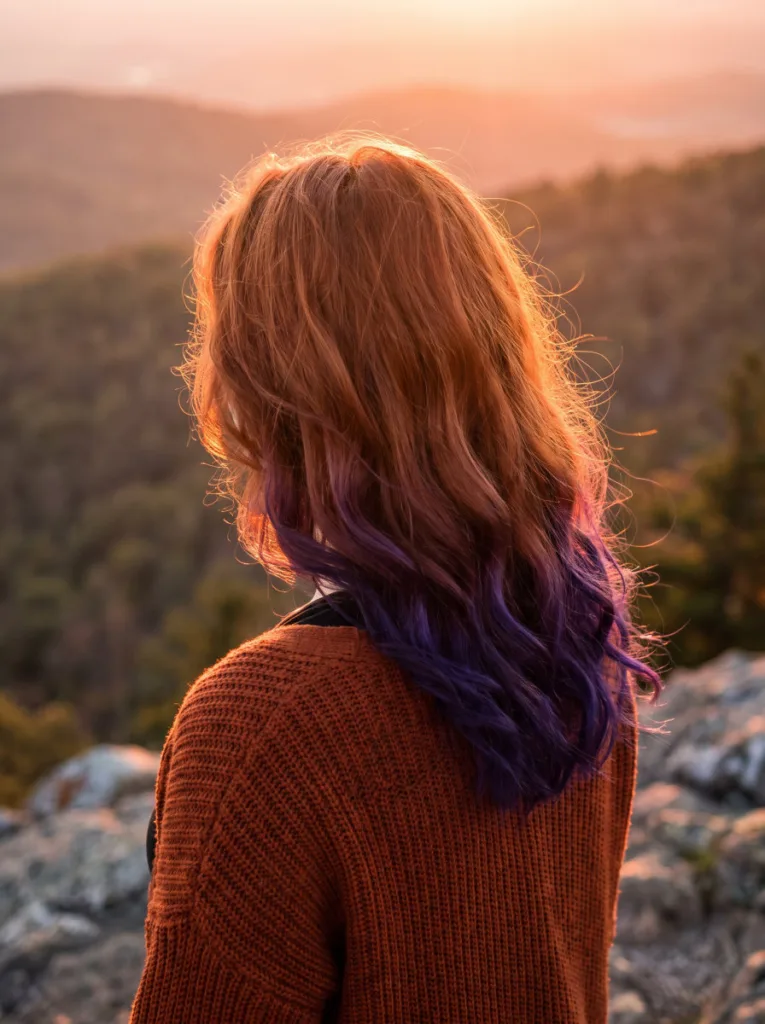 Woman with copper roots deepening into violet hair color ends