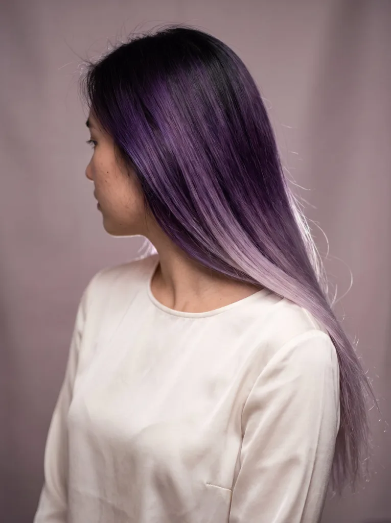 Woman with deep violet to lilac melt gradient hair color on long straight hair