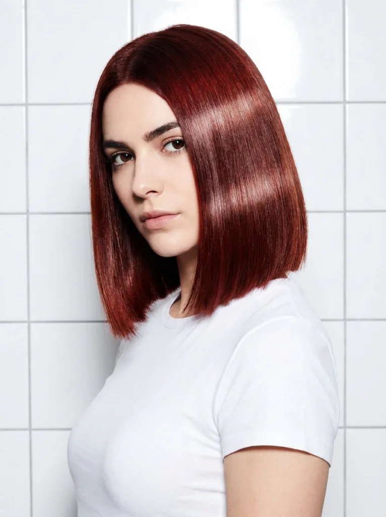 Thick blunt bob in garnet copper with a high-shine red-violet finish