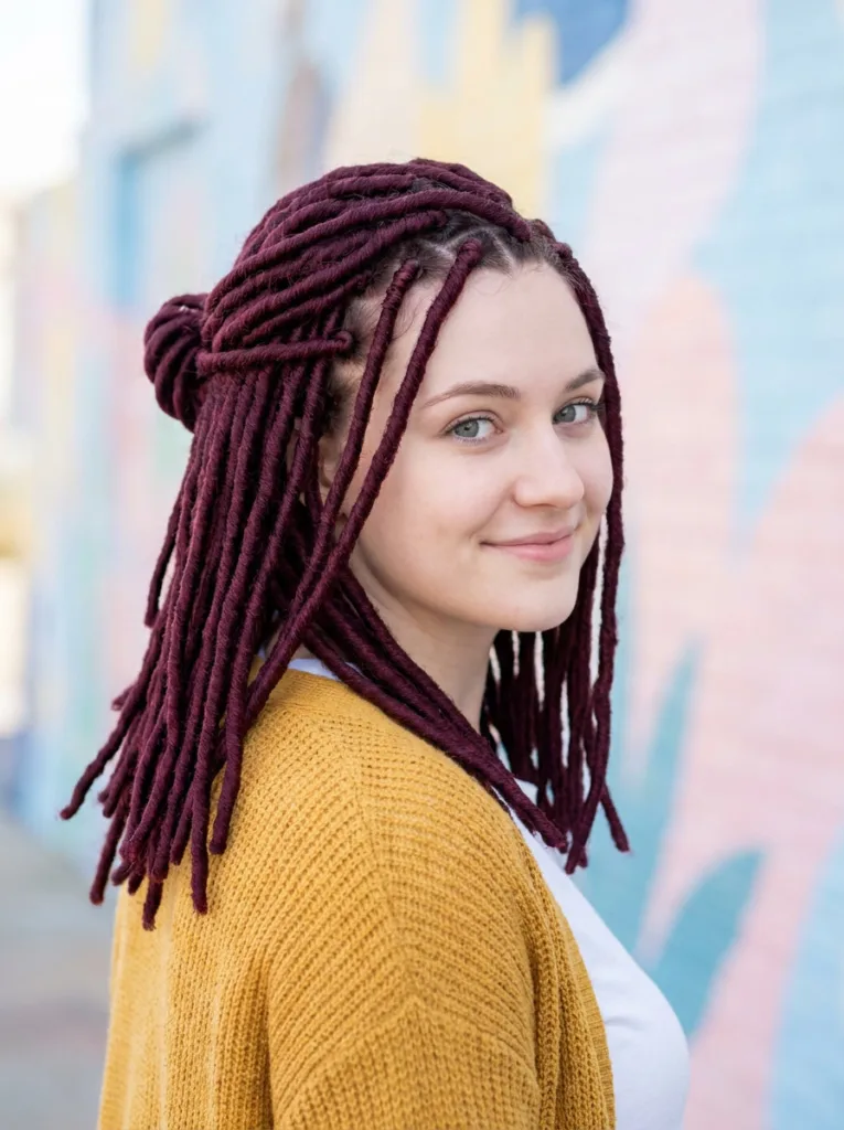 Shoulder length faux locs styled half up with a loose knot, a style that suits faux locs