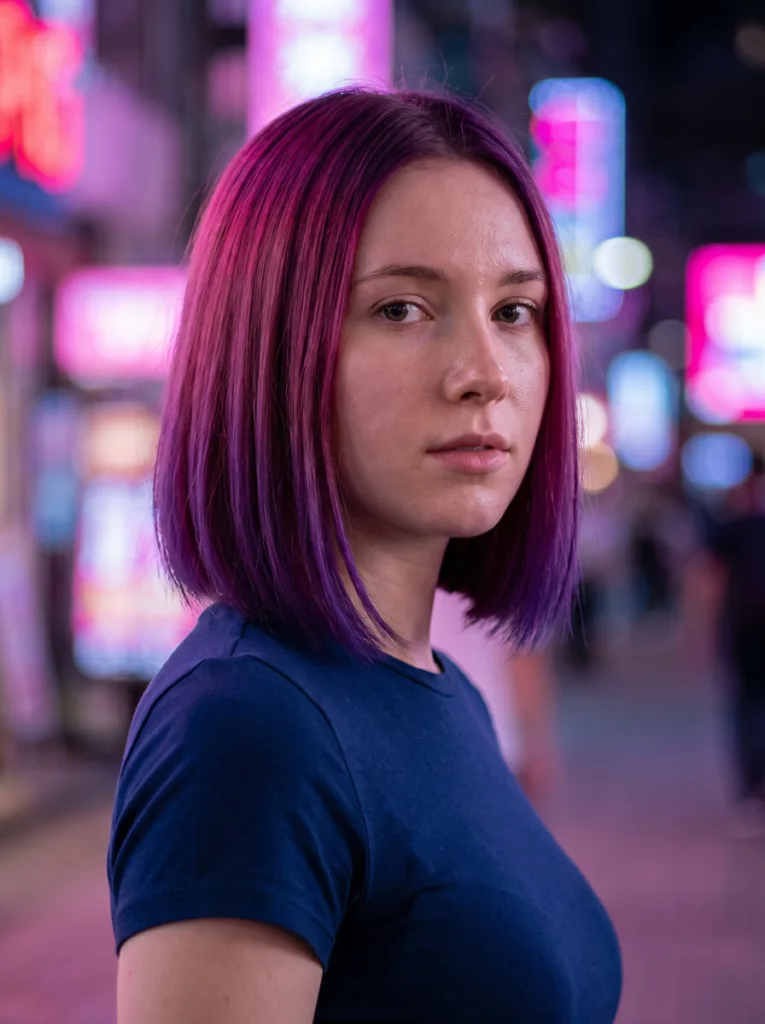 Woman with magenta to violet reverse gradient hair color on a bob haircut