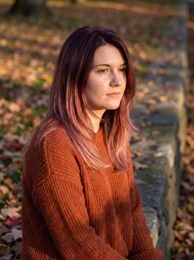 Woman with plum roots fading into rose gold hair color ends