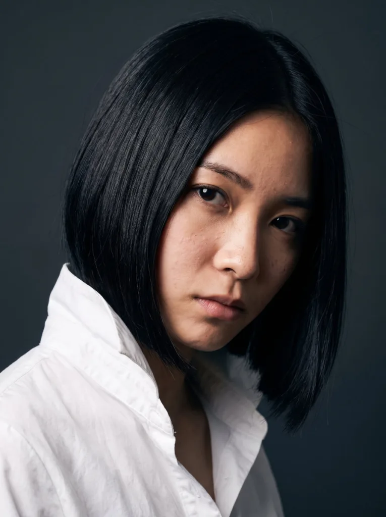 Woman with a dramatic angled bob haircut, short in back and long in front, photographed in profile