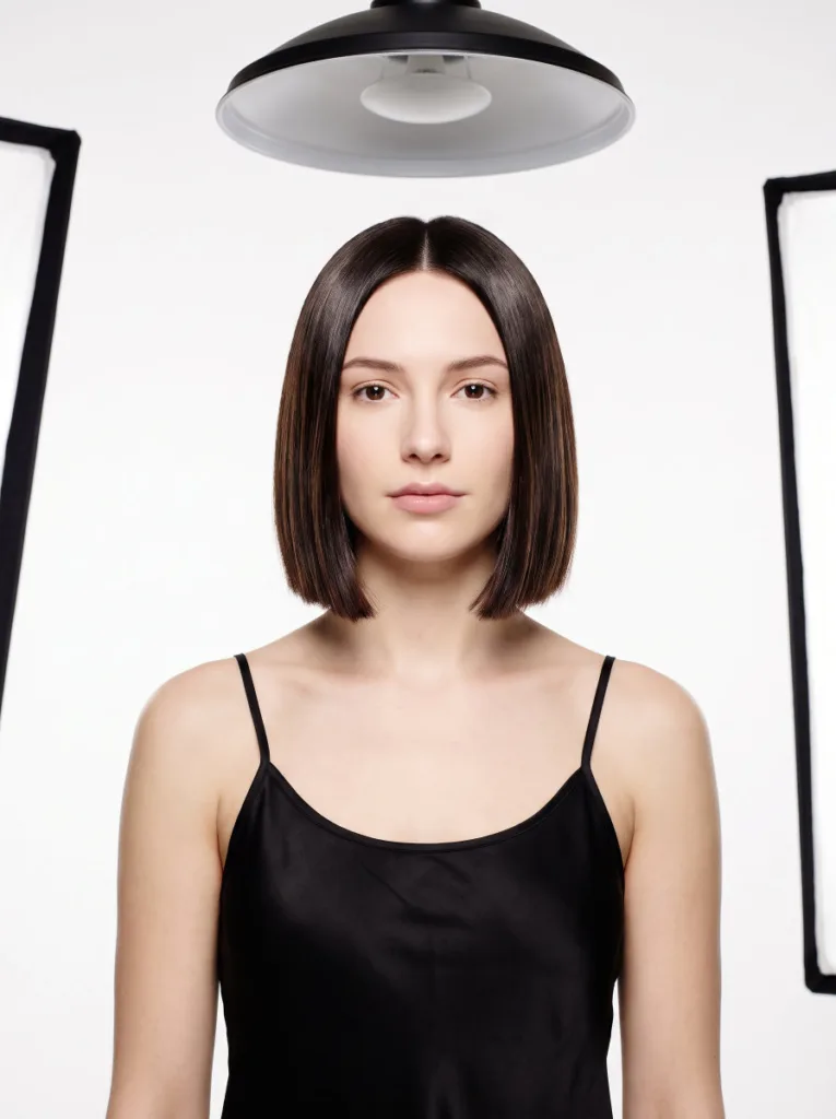 Woman with a sleek, glass-like chin-length bob haircut in a clean studio portrait