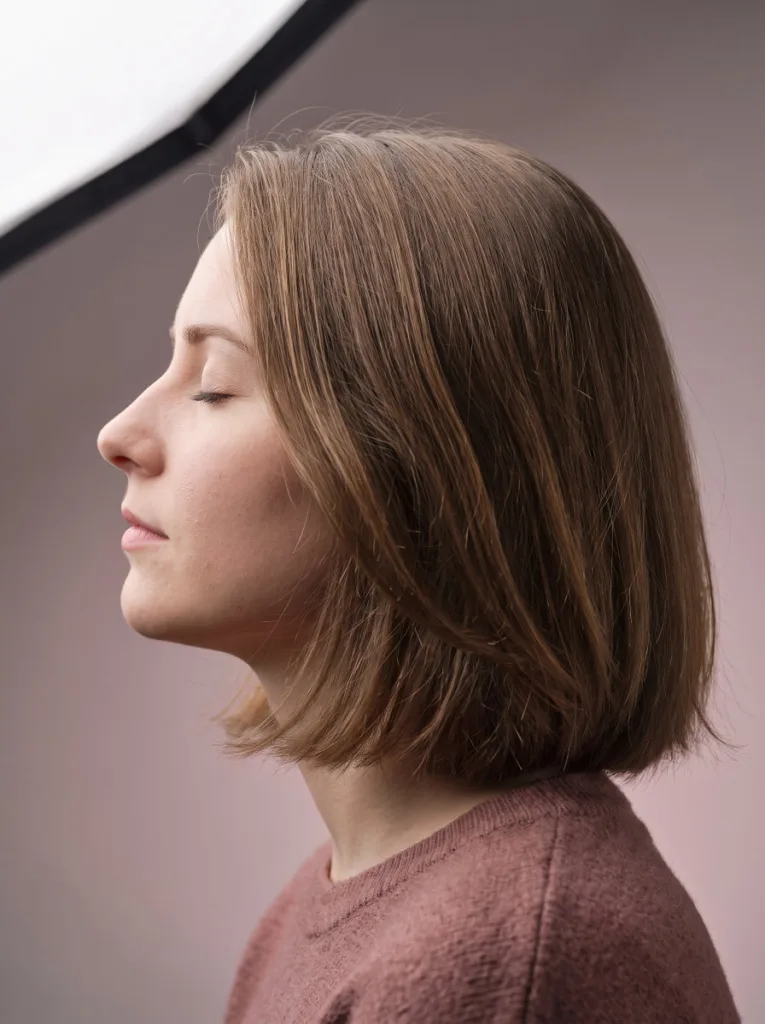 Side profile of a woman with a soft layered bob haircut showing gentle layers beneath the cheekbone