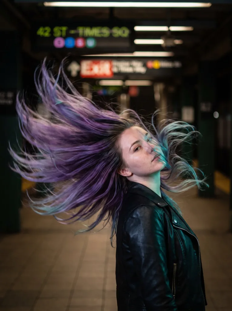 Woman with violet to teal split gradient hair color captured in motion