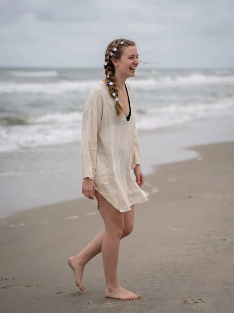 Woman walking on a beach with a waterfall braid decorated with small seashell clips