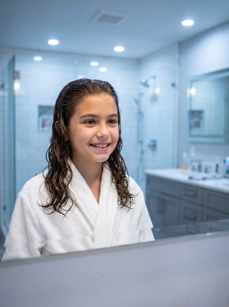 Girl with a sleek wet-look wave hairstyle in a bathroom mirror