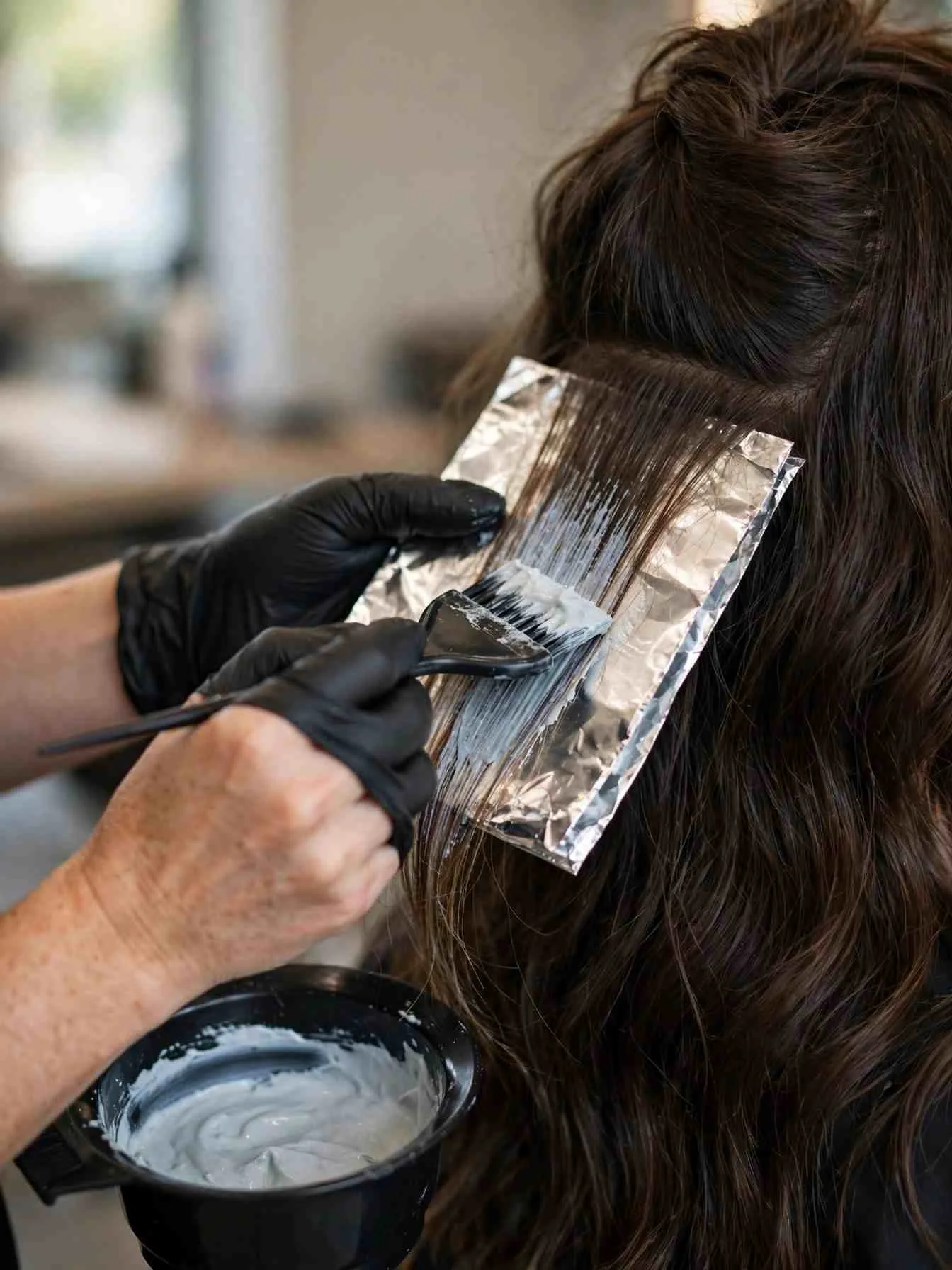 Stylist painting balayage highlight strands in a salon