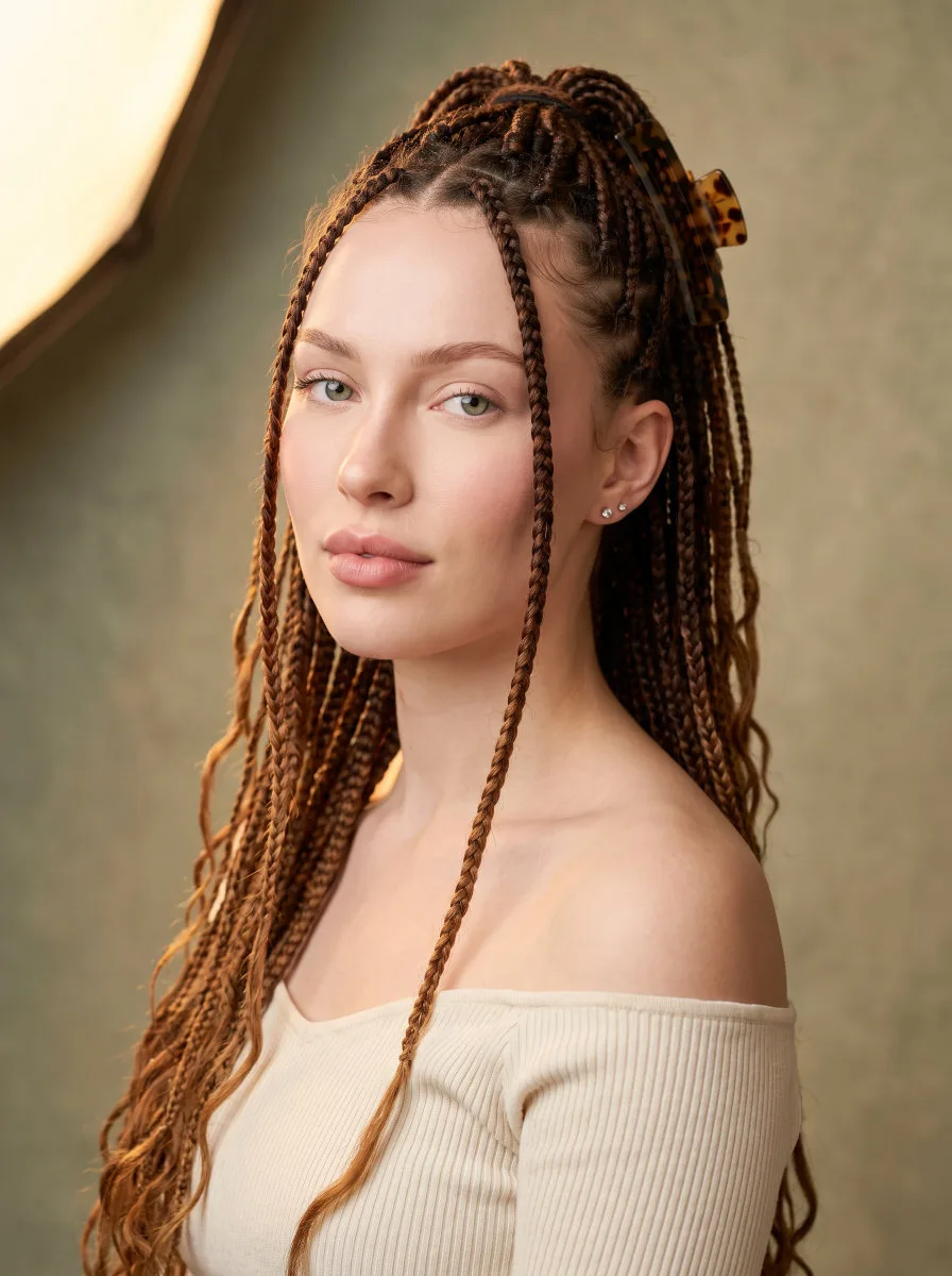 Beautiful young woman with medium knotless braids in chestnut-to-caramel ombre styled half-up