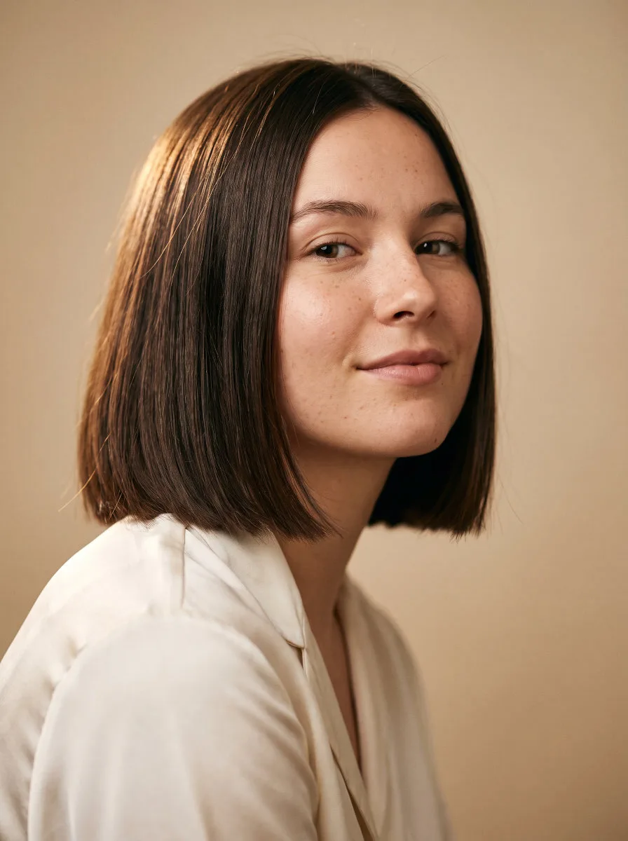 Collage-style portrait of a woman with a shiny blunt bob haircut against a soft studio backdrop, representing stunning bob haircuts