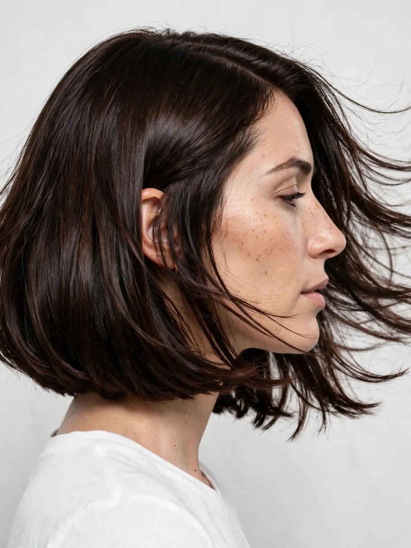 Italian Bob Haircut: The Full Guide to Getting It Right 1 Side profile of a woman with a glossy dark brown Italian bob haircut, full ends between chin and collarbone