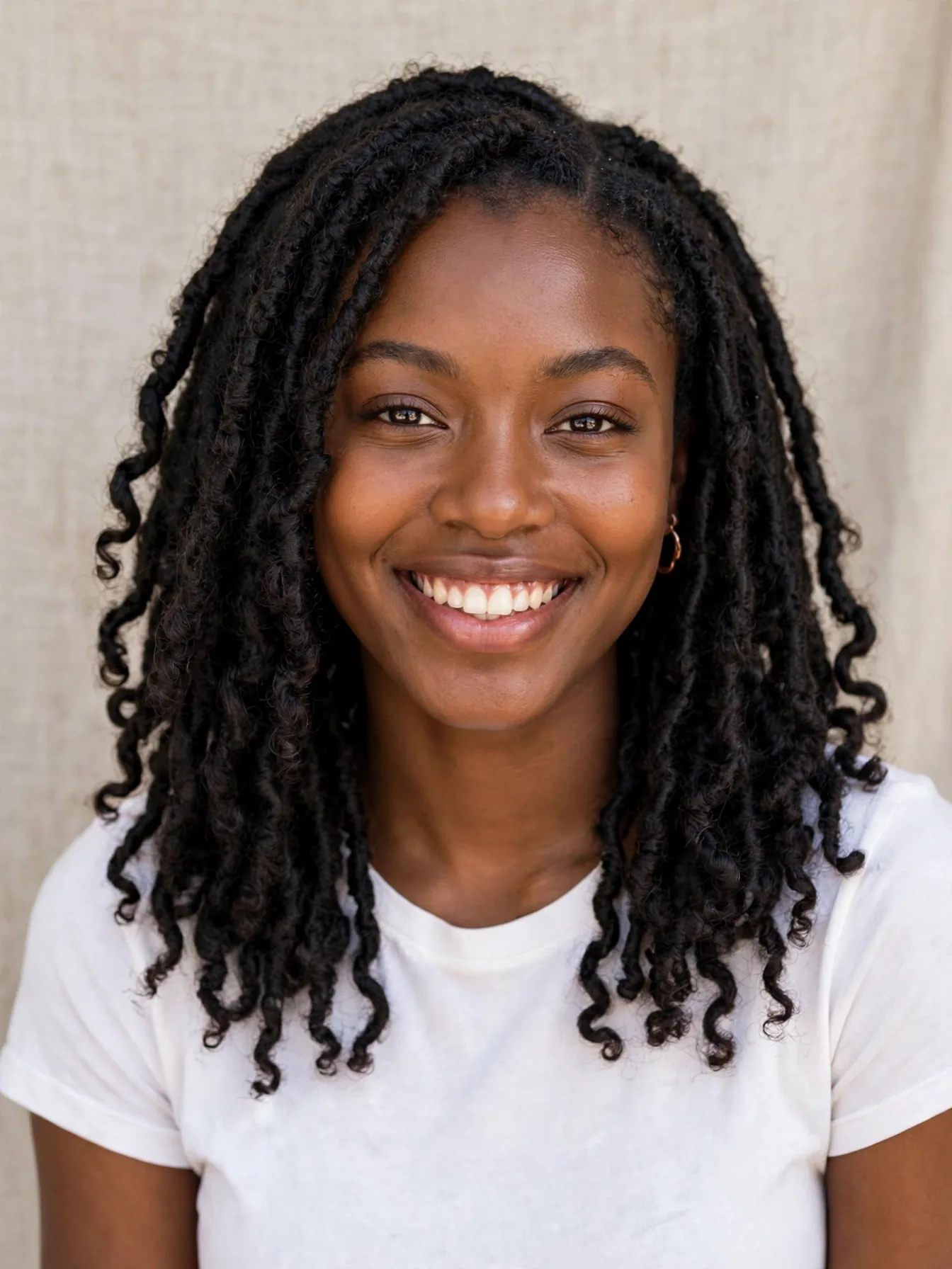 Smiling woman with shoulder-length black butterfly locs hairstyles